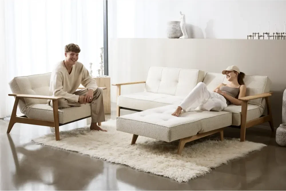 Sovesofa Splitback frej Fra Innovation Living i lys tekstil med to personer som koser seg.