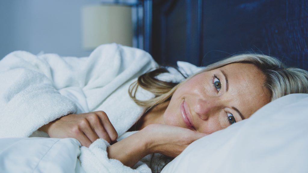 kvinne liggende i seng, close up ansikt